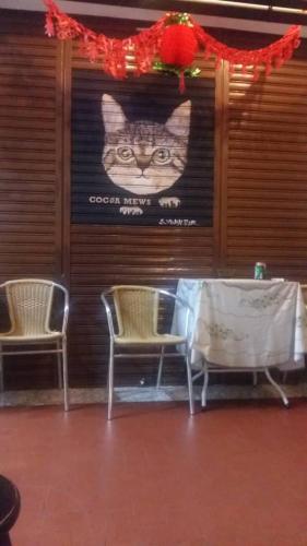 a poster of a cat on a wall with two chairs at Cocoa Mews Cafe and Homestay in George Town