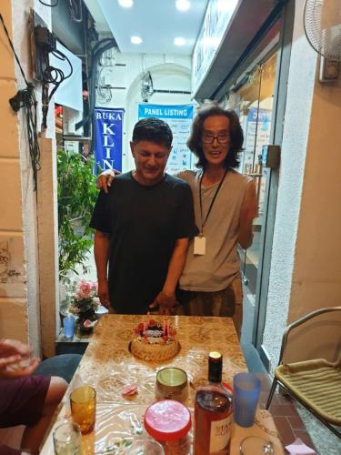 a man and a woman standing next to a table with a cake at Cocoa Mews Cafe and Homestay in George Town