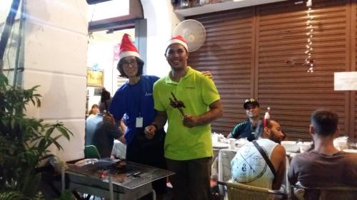 a man wearing a santa hat standing next to two people at Cocoa Mews Cafe and Homestay in George Town