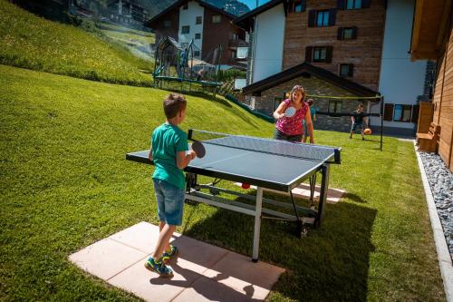 un joven jugando ping pong en una mesa de ping pong en B&B AZapartments Lunic, en Grächen