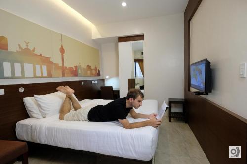 a man laying on a bed with a tablet at Bed and Bath Serviced Suites in Iloilo City