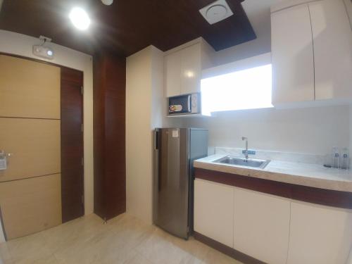 uma cozinha com armários brancos e um frigorífico de aço inoxidável em Bed and Bath Serviced Suites em Iloilo