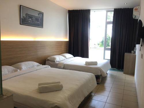 een hotelkamer met 2 bedden en een raam bij Place2Stay @ Kenyalang in Kuching