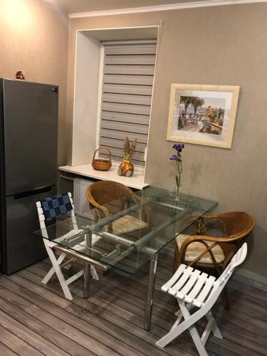 a glass table in a kitchen with chairs and a refrigerator at DAUGAVPILS in Daugavpils