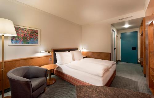 une chambre d'hôtel avec un lit et une chaise dans l'établissement Seminaris Hotel Leipzig, à Leipzig