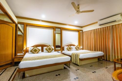 a hotel room with two beds and a ceiling fan at Garden Hotel in Mumbai