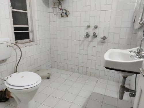 a white bathroom with a toilet and a sink at Hotel Madhuban Shimla in Shimla