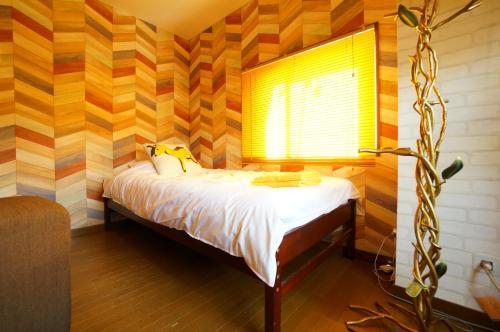 a small bedroom with a bed with a window at Tomato Takayama Station in Takayama