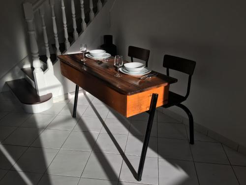 a wooden table with plates and glasses on it next to stairs at Les Gîtes du Château de Passillé in Parigné