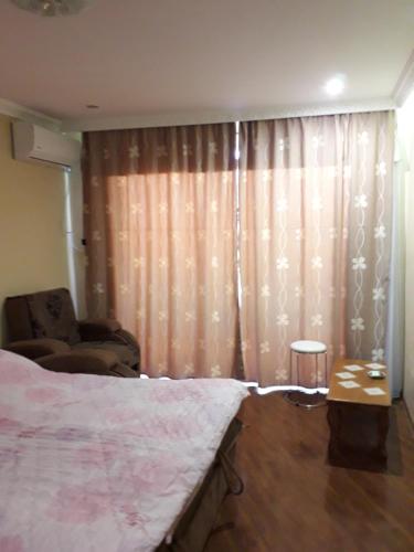 a bedroom with a bed and a chair and curtains at Сергей Сергеевич in Akhaltsikhe