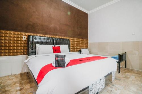 um quarto com uma grande cama branca e um cobertor vermelho em RedDoorz near Millennium ICT Center Medan em Medan