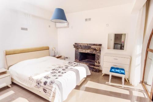 a white bedroom with a bed and a fireplace at Bellapais Apartments in Kérynia