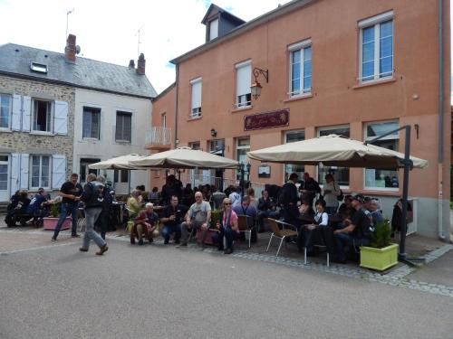 a group of people sitting under umbrellas on a street at Le Lion D'or in Ouroux en Morvan