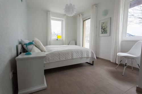 a white bedroom with a bed and a chair at Das gelbe Haus 1 in Winterberg