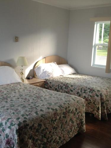 a hotel room with two beds and a window at Hôtel Motel du Rocher in Rivière-la-Madeleine