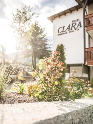 a woman sitting in front of a building at Hotel Clara in Bressanone