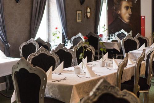 une salle à manger avec des tables et des chaises et un portrait d'un homme dans l'établissement Hotel Fryderyk, à Duszniki-Zdrój