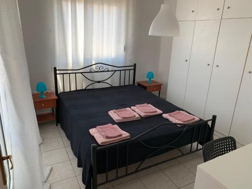 una camera da letto con un letto nero e asciugamani rosa di Apartment 30m from the sea a Salonicco