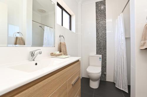 Baño blanco con lavabo y aseo en Morphettville Motor Inn en Glenelg