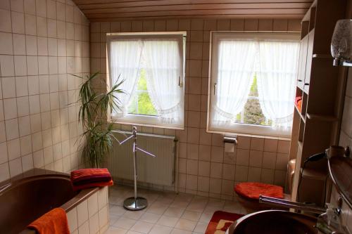 a bathroom with a tub and a toilet and two windows at Ferienwohnung Eggers in Bispingen
