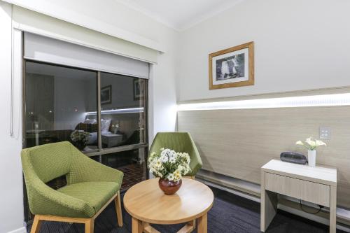 a room with two chairs and a table with flowers at Morphettville Motor Inn in Glenelg