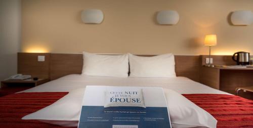 a hotel room with a bed with a book on it at Kyriad Genève St-Genis-Pouilly in Saint-Genis-Pouilly