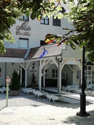 a large white building with white tables in front of it at Siesta Club Apartman Harkány in Harkány