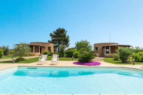 a swimming pool with two chairs and a house at Li Furneddhri (Trulli) in Casarano