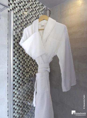 Un peignoir blanc est suspendu dans la douche. dans l'établissement Hôtel Bassano, à Paris