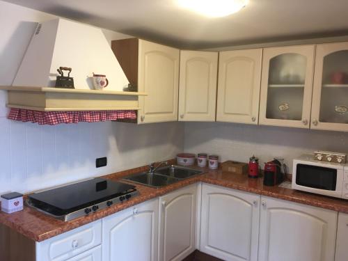 a kitchen with white cabinets and a sink and a microwave at La casa di Rosy in Enego