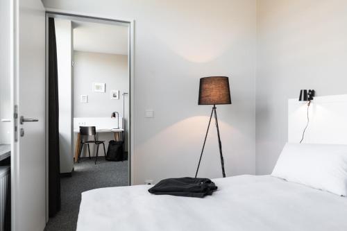 Zimmer mit einem Bett, einem Spiegel und einer Lampe in der Unterkunft HUB Apartments in Hamburg