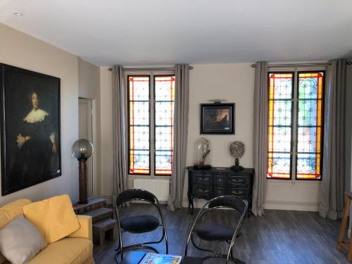een woonkamer met een bank, stoelen en ramen bij Le 39 Bis in Rémalard