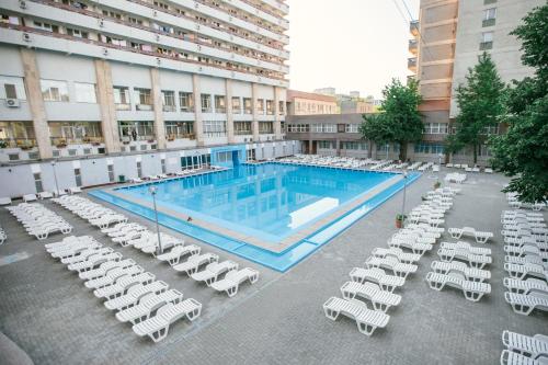 una gran piscina con sillones blancos y un hotel en Hotel Mures, en Băile Felix