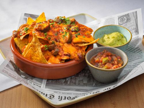 a plate of food with nachos and a bowl of dips at H10 Casa del Mar in Santa Ponsa