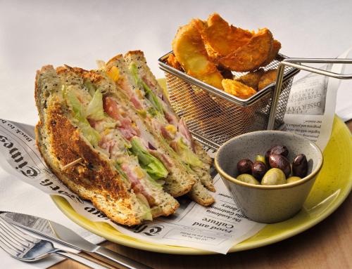 a yellow plate with a sandwich and a basket of food at H10 Casa del Mar in Santa Ponsa