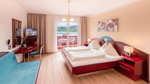 a bedroom with a bed and a desk and a room at Strandhotel Orchidee in Sankt Kanzian