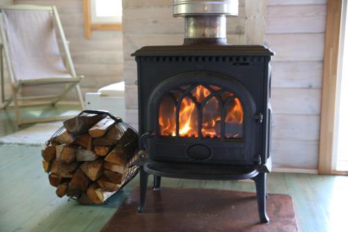 a black stove in a living room with a fire at Viesu mājas Briedīši in Raiskums