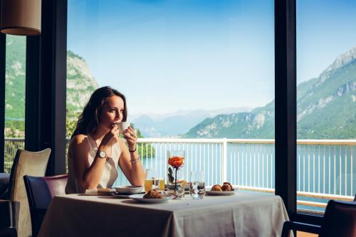 Eine Frau, die an einem Tisch vor einem Fenster sitzt. in der Unterkunft Hotel Griso Collection in Malgrate