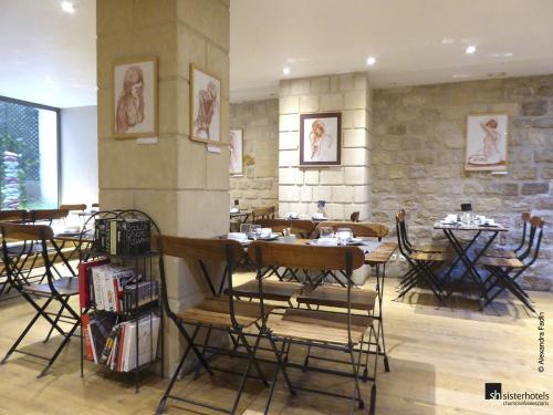ein Restaurant mit Tischen und Stühlen und einer Steinmauer in der Unterkunft Tilsitt Etoile Paris in Paris