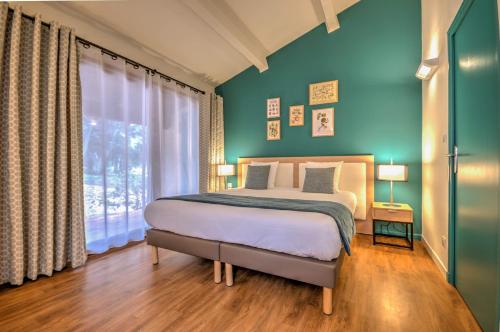 a bedroom with a bed with blue walls and a window at Best Western Domaine de Roquerousse in Salon-de-Provence