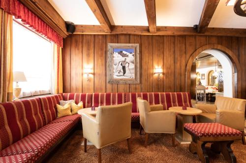a restaurant with a red couch and chairs and a table at Hotel Alpina Superior in Pettneu am Arlberg