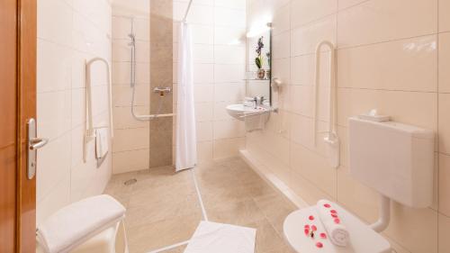 a white bathroom with a shower and a toilet at Strandhotel Orchidee in Sankt Kanzian