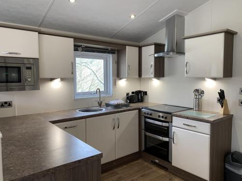 a kitchen with white cabinets and a sink at Riverside Rothbury Superior Lodge in Rothbury