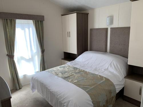 a bedroom with a large bed and a window at Riverside Rothbury Superior Lodge in Rothbury