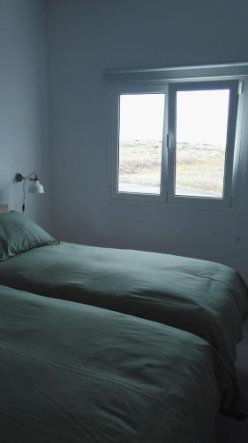a bedroom with a bed and two windows at Beautiful Apartament Arrieta in Haría