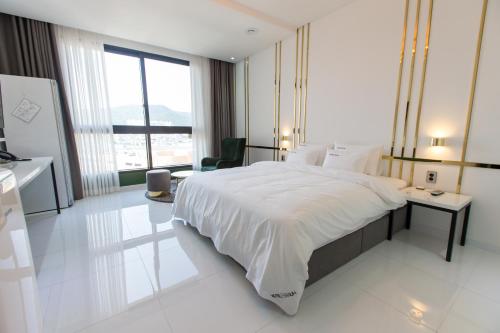 a white bedroom with a large bed and a desk at Hotel Raum Suncheon in Suncheon