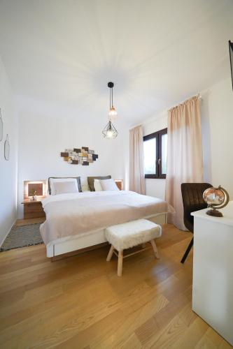a white bedroom with a large bed and a chair at Villa Suncica with Heated Pool, Jacuzzi and Bikes near Zadar in Sukošan