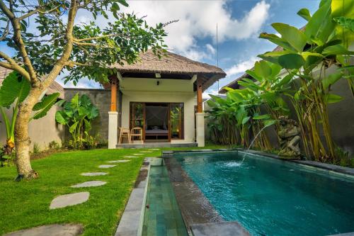a villa with a swimming pool in front of a house at Three Gold Luxury Private Villas in Ubud
