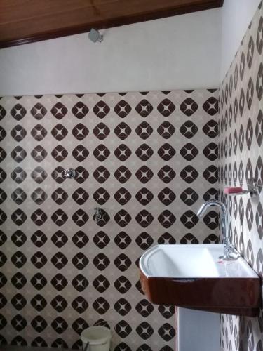 baño con lavabo y pared de azulejos blanco y negro. en Vamoose Jharna Tabakoshi, en Mirik