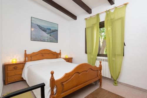 a bedroom with a wooden bed and a window at Ca Na Sioneta in Campanet